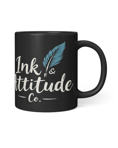 Black ceramic mug featuring the text "Ink & Attitude Co." with a blue feather design. Ideal for writers and creatives.