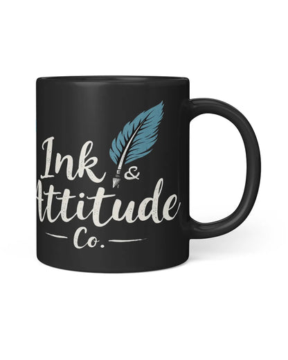 Black coffee mug featuring the text "Ink & Attitude Co." with a feather design, ideal for early risers.