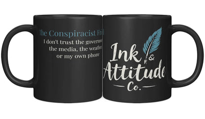 Black ceramic mug featuring "The Conspiracist Friend" text on one side and "Ink & Attitude Co." logo on the other.